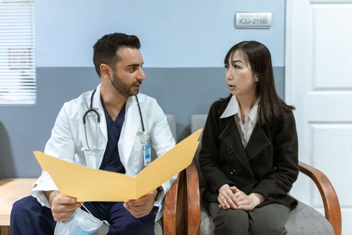 Doctor holding a folder while talking with a patient in a waiting area