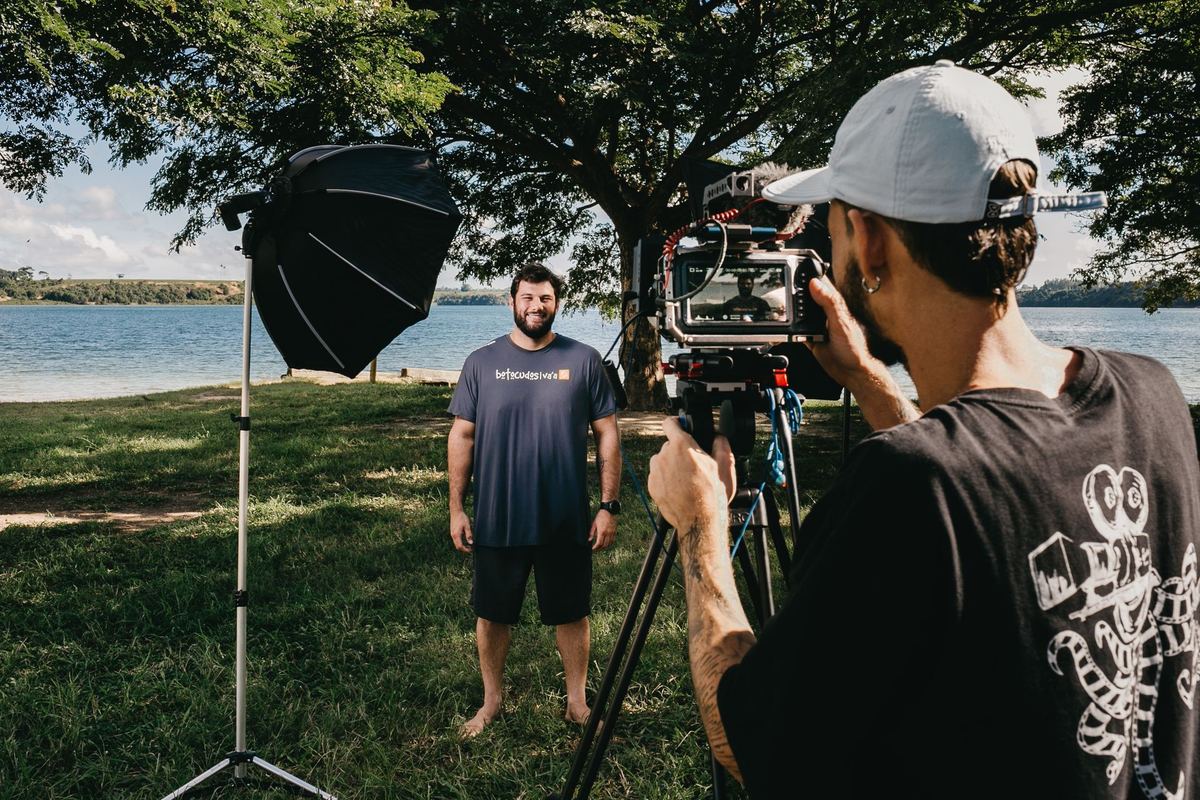 Cameraman filming a man outdoors beside a lake