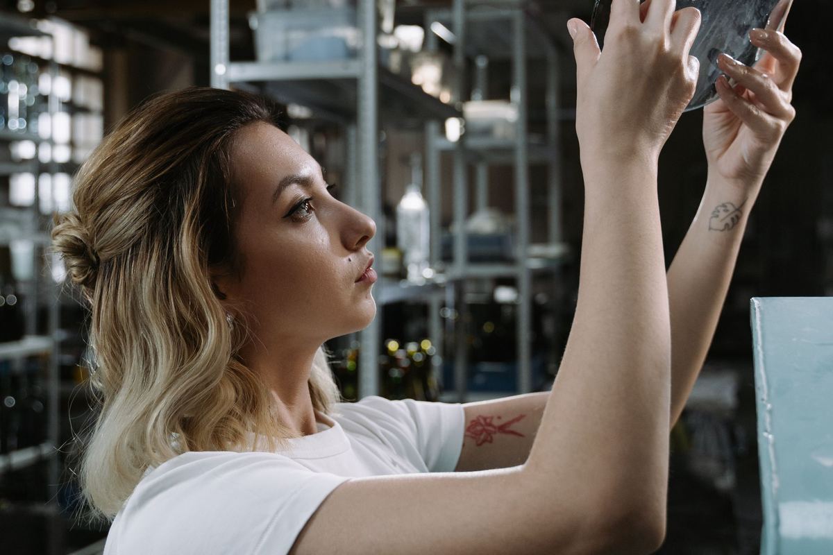Woman inspecting a metal piece held up to the light in a workshop