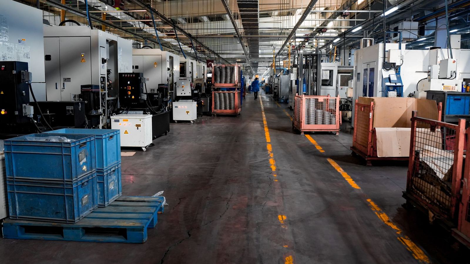 Industrial photography of a wide manufacturing facility floor with machinery and crates