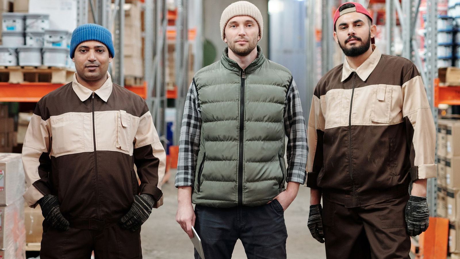 Three warehouse crew members standing in a warehouse aisle
