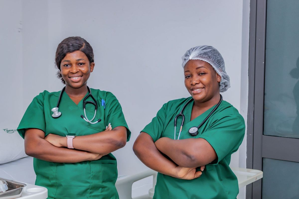 Two nurses in scrubs smiling in a hospital