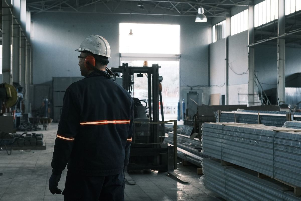 Worker in protective gear supervising a production line during a plant tour