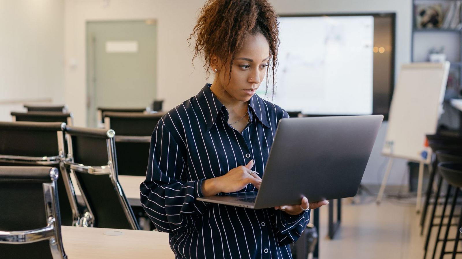 New employee standing in a training room while using a laptop