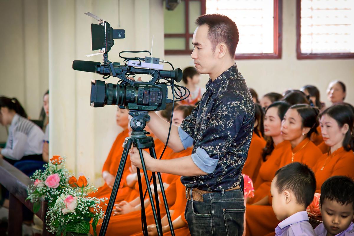 Cameraman filming with a professional video camera on a tripod at an indoor event
