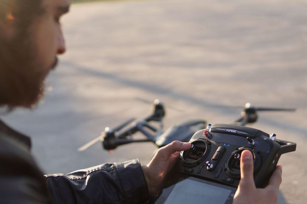 Drone operator holding a controller with the drone on the ground in front of him