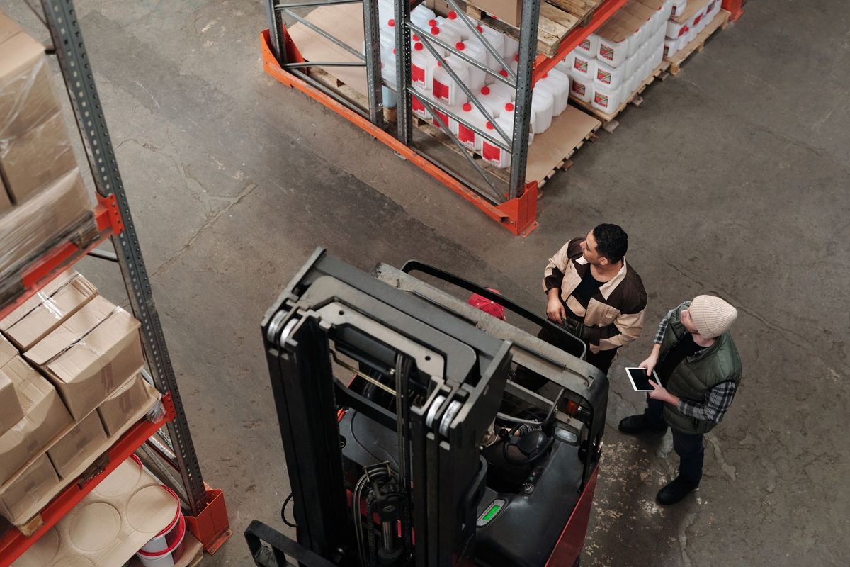 Two workers discussing a forklift check in a warehouse