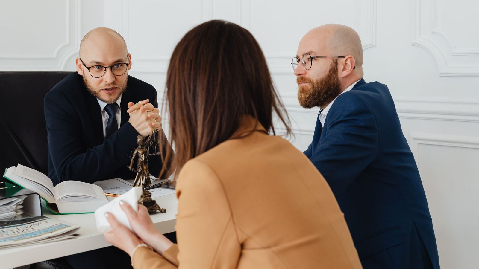 Attorneys talking with a client across a desk in a law office